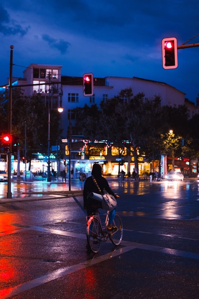 黑夹克男子骑自行车在夜间道路

